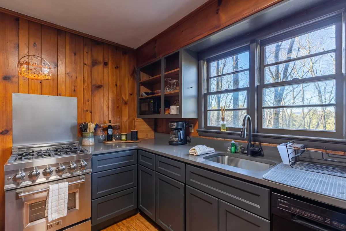 Focusing on the kitchen, this image features a modern stainless steel stove, quartz kitchen counters, large windows, and wooden walls. The space is bright yet warm, emphasizing culinary adventures and meal prep with family and friends.
