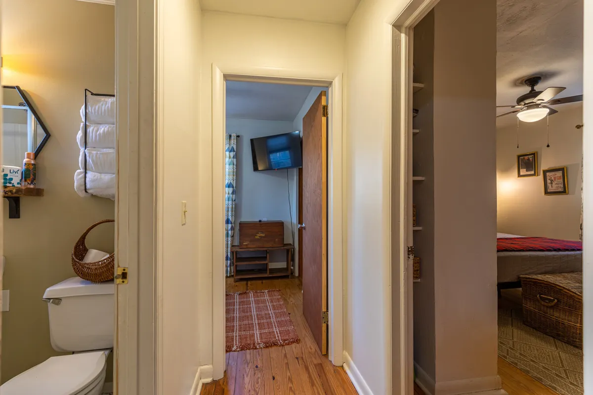 A cozy bedroom scene featuring a comfortable bed, wooden furniture, a mirror, and a television. The space suggests a relaxing atmosphere for unwinding after a day of adventure, with natural light filtering in and touches that make it feel like a welcoming home base.